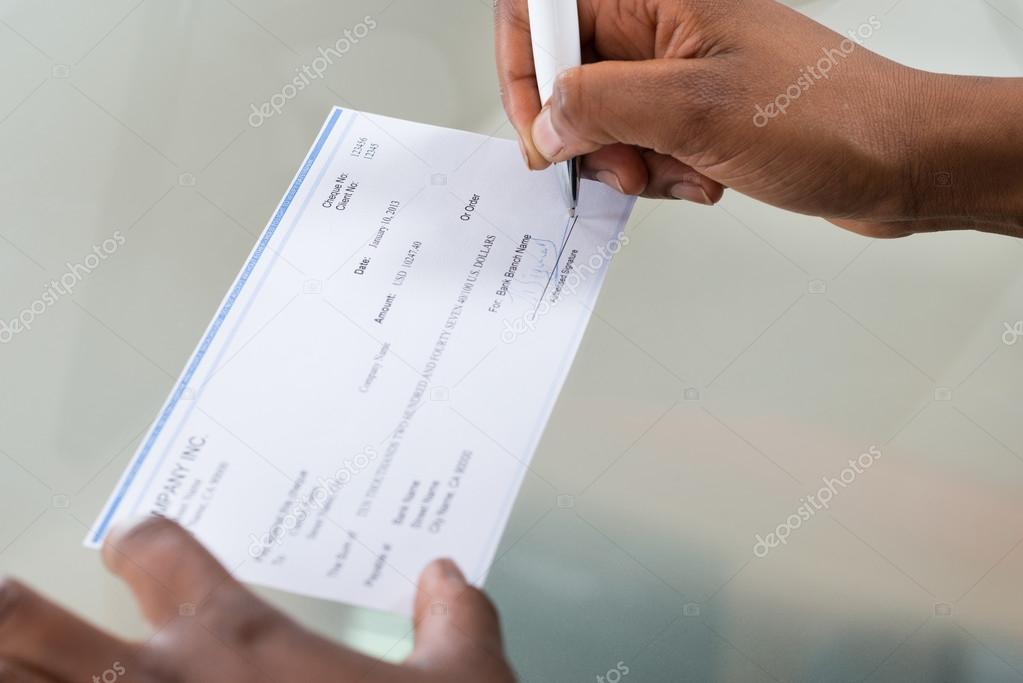 Person's Hand Signing Cheque