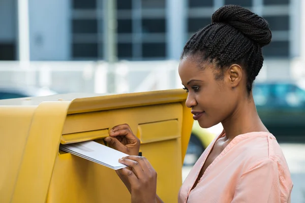 Женщина вставляет письмо в почтовый ящик — стоковое фото