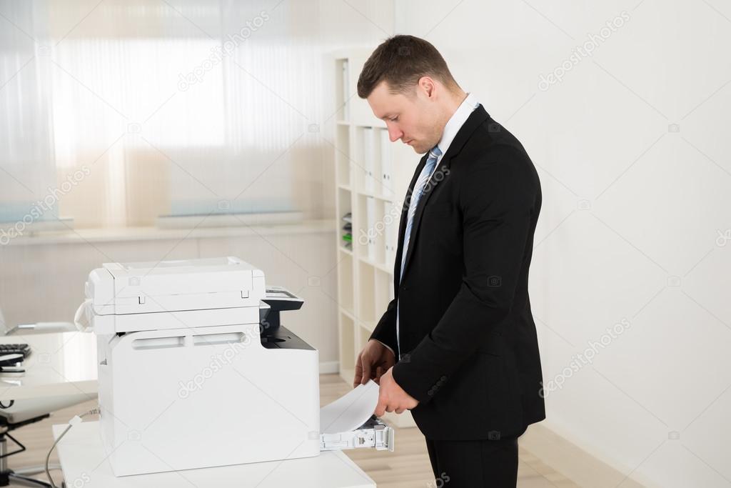 Businessman Inserting Paper In Photocopy Machine