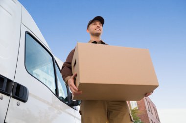 Karton kutu taşıyan teslimatçı.