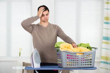 Tired Man Looking At Laundry Basket clipart