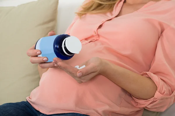Terhes nő tabletták ömlött a kezében, üveg — Stock Fotó