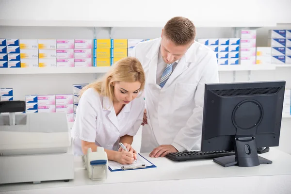 Pharmacists Maintaining Checklist At Counter In Pharmacy — Stock Photo, Image