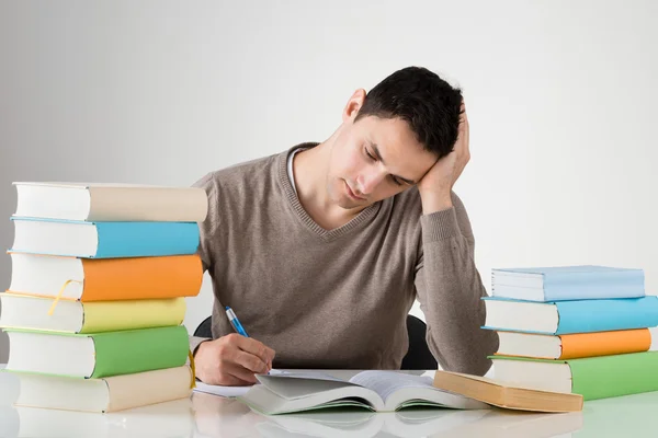 Wyczerpany mężczyzna studiuje w tabeli — Zdjęcie stockowe