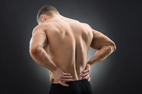 Мускулистый человек, страдающий от боли в спине — стоковое фото