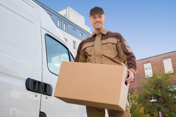 Entrega homem transportando caixa de papelão — Fotografia de Stock