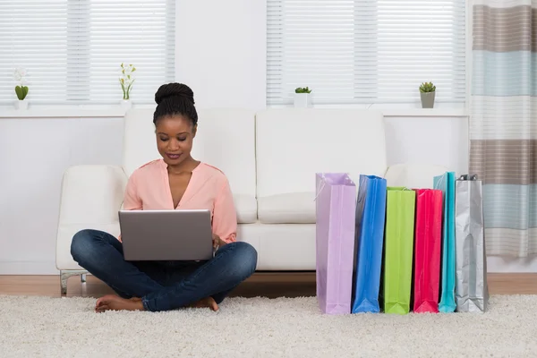 Frau sitzt auf Teppich beim Online-Shopping — Stockfoto