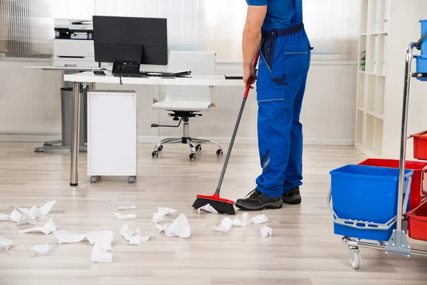 Vaktmästaren sopa golvet med kvast i Office — Stockfoto