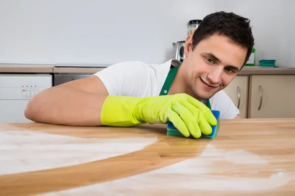 Man rengöra damm på träbord — Stockfoto