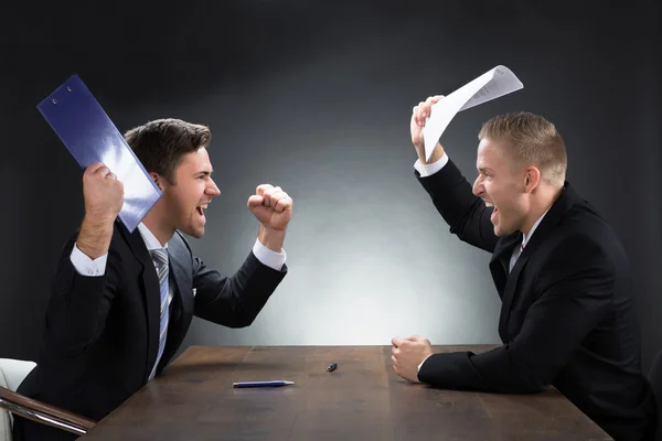 Агрессивные молодые бизнесмены спорят за столом — стоковое фото