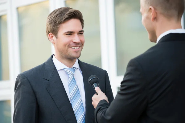 Журналист берет интервью у счастливого бизнесмена — стоковое фото