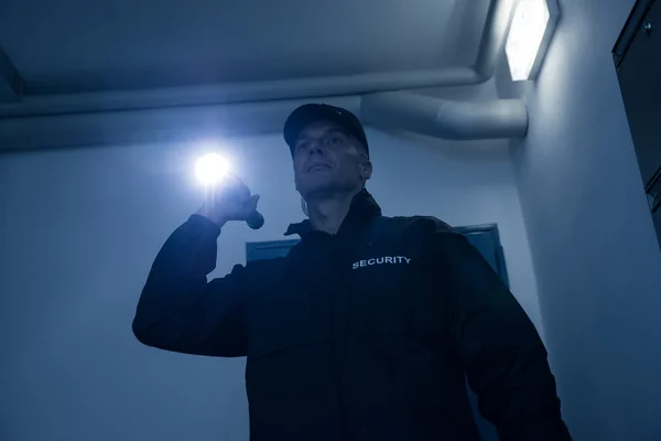 Охранник ищет с фонариком в офисе — стоковое фото