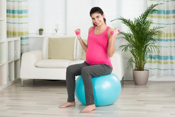 Feliz mulher grávida levantando halteres — Fotografia de Stock