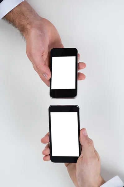 Empresários usando telefones celulares na mesa — Fotografia de Stock