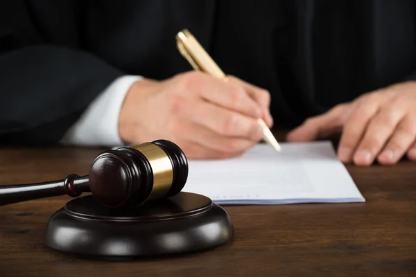 Soudce psaní na právní dokumenty na stůl — Stock fotografie