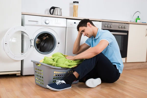 Hombre ensensed mirando la cesta de la lavandería por la lavadora — Foto de Stock