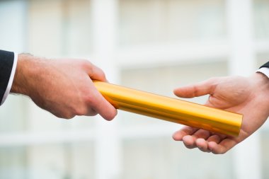 Businessman Giving Relay Baton To Colleague