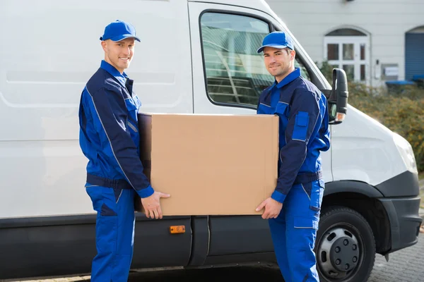 Homens de entrega transportando caixa de papelão — Fotografia de Stock