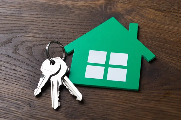 Grünes Papierhaus und Schlüssel auf dem Tisch — Stockfoto