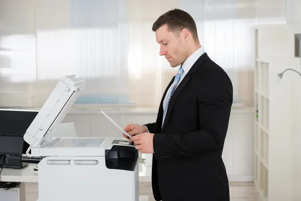 Geschäftsmann mit Fotokopiergerät im Büro — Stockfoto