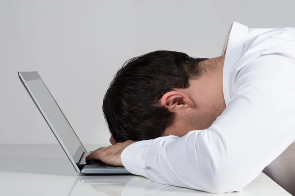 Zakenman leunend op Laptop aan balie benadrukt — Stockfoto