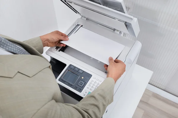 Empresario manteniendo papel en la máquina — Foto de Stock