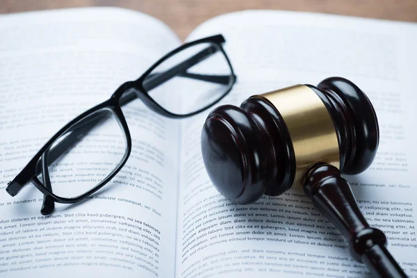 Mallet och glasögon på öppen rättsliga bok — Stockfoto