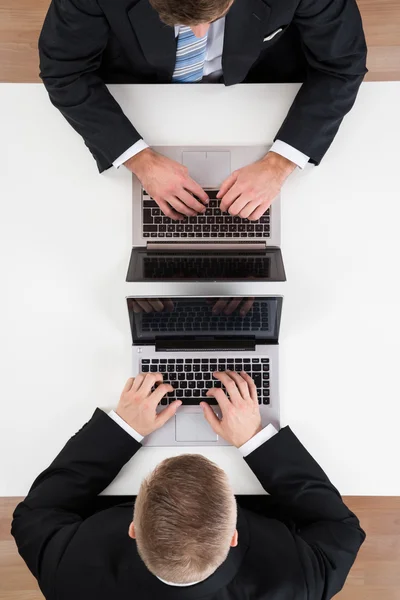 Uomini d'affari che utilizzano i computer portatili a tavola — Foto Stock