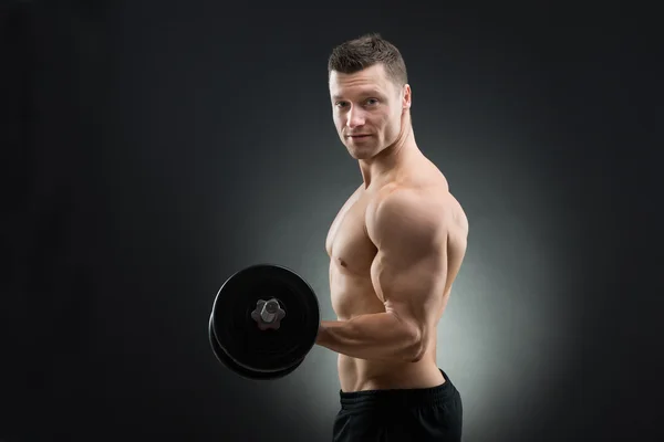 自信を持って筋肉男を持ち上げるダンベル — ストック写真