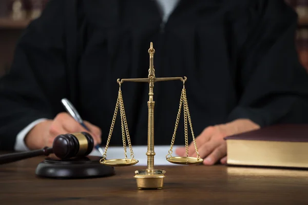 Escalas de lei na mesa com juiz — Fotografia de Stock