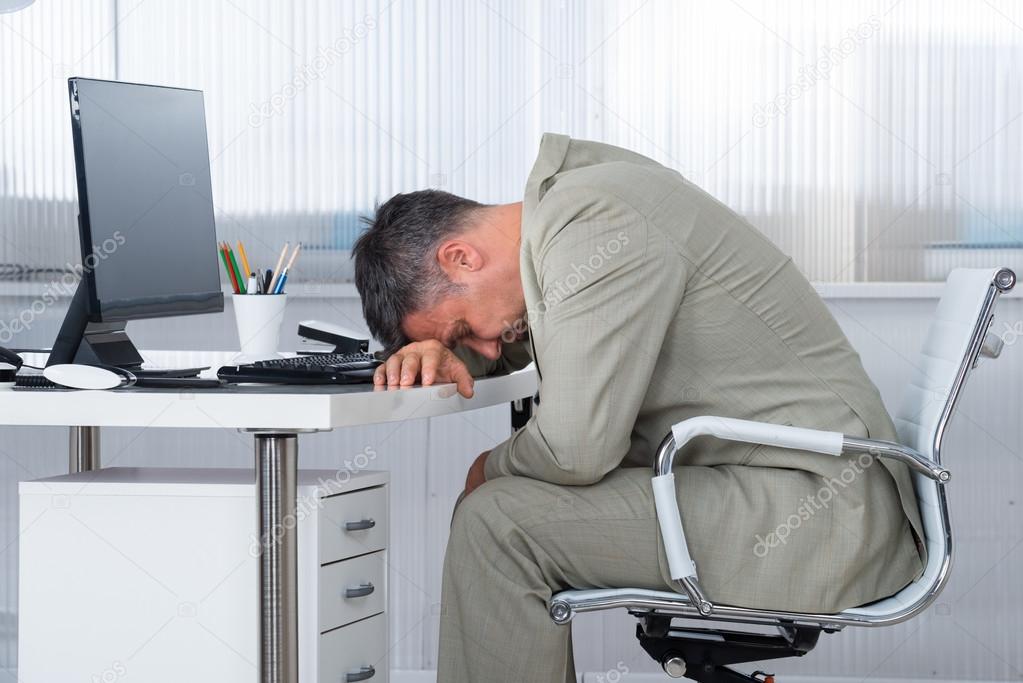 Businessman Sleeping On Desk In Office