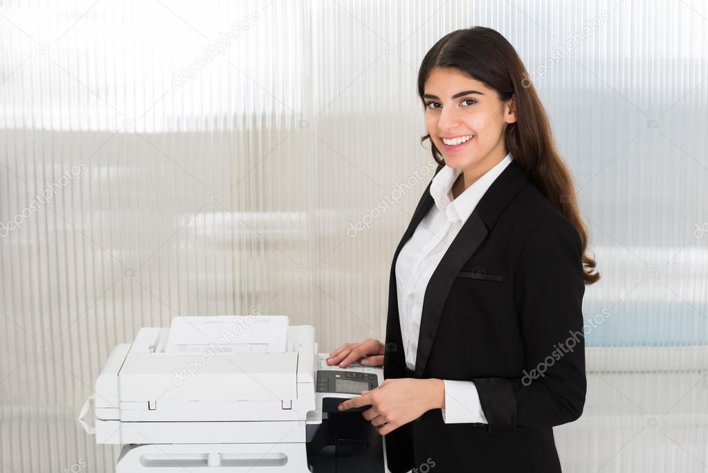Businesswoman Using Photocopy Machine In Office