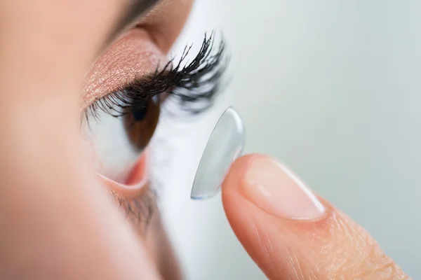 Žena doma nosí kontaktní čočky — Stock fotografie