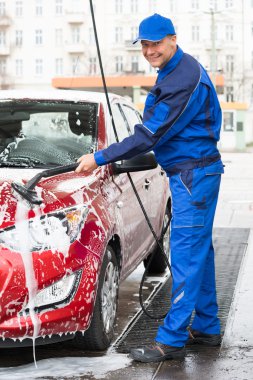 Confident Male Worker Washing  Car clipart