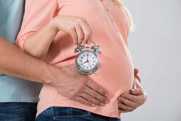 Mujer embarazada sosteniendo el despertador — Foto de Stock