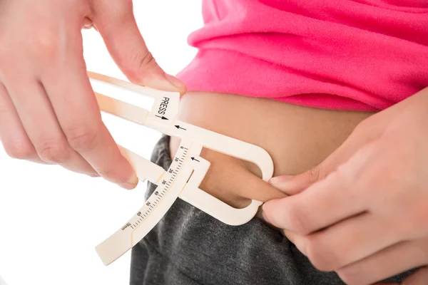 Женщина измеряет жиры с помощью калипера — стоковое фото