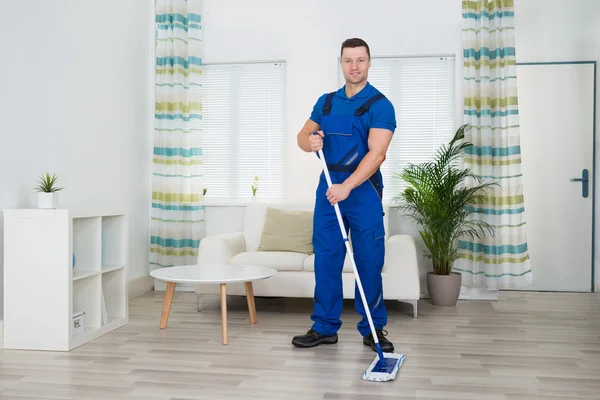 Glimlachend werknemer reiniging van de vloer — Stockfoto