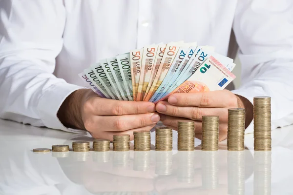 Geschäftsmann fächerte Euro-Scheine mit Münzen auf — Stockfoto