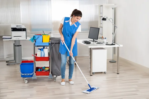 Lyckliga kvinnliga vaktmästaren Mopping golv — Stockfoto