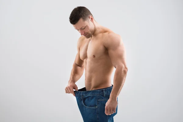 Hombre muscular mirando la pérdida de peso — Foto de Stock