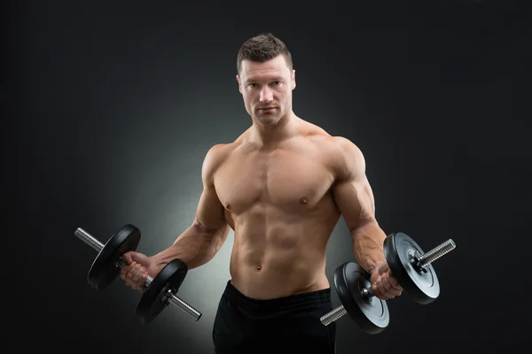 Uomo muscoloso che tiene i manubri — Foto Stock