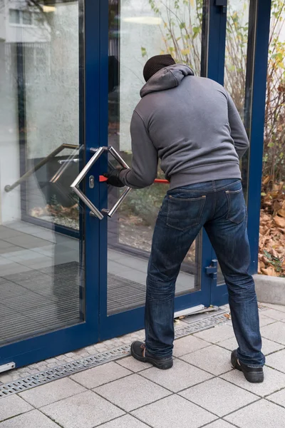 Mann öffnet Tür mit Brecheisen — Stockfoto