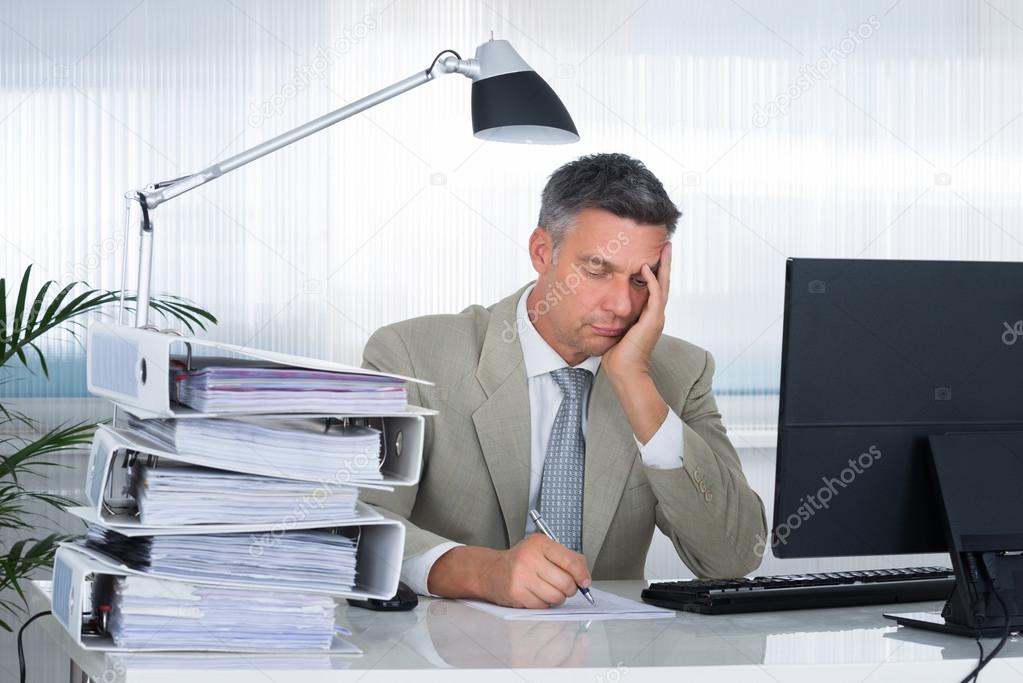 Tired Businessman Writing On Document
