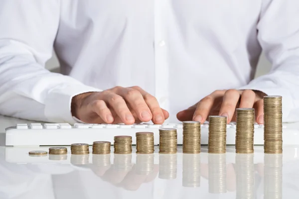 Empresario usando teclado de computadora con monedas —  Fotos de Stock