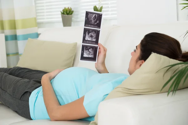 Těhotná žena při pohledu na ultrazvukové vyšetření — Stock fotografie