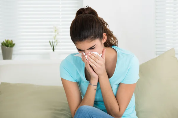 Frau pustet Nase auf Sofa — Stockfoto