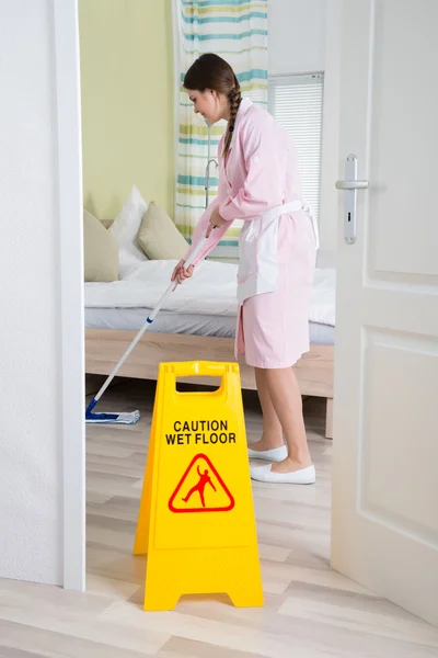 Vrouwelijke huishoudster schoonmaken vloer — Stockfoto