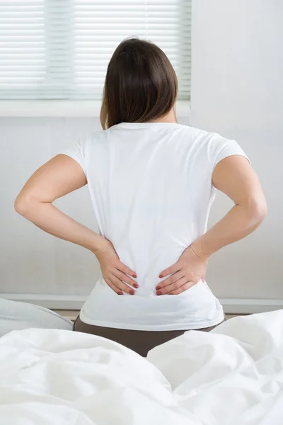 Mujer con dolor de espalda sentada en la cama — Foto de Stock