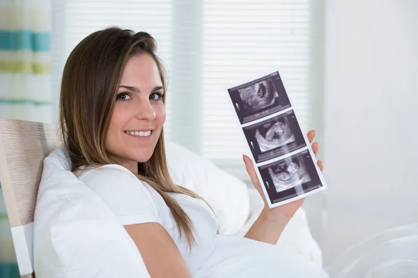 Mujer joven sosteniendo foto de ultrasonido — Foto de Stock