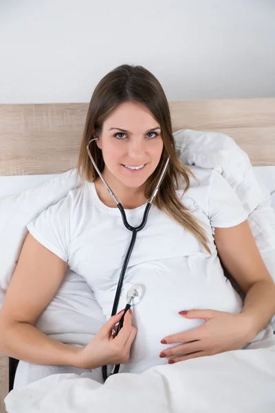 Mujer examinándose con estetoscopio —  Fotos de Stock